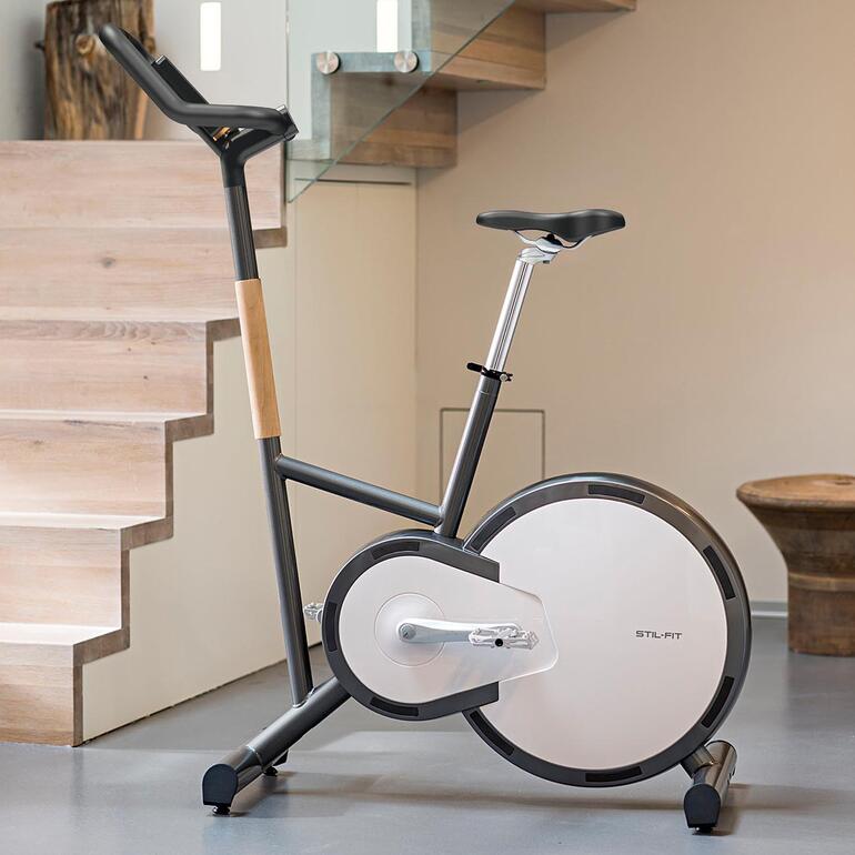 Modernes Ergometer-Fahrrad in einem stilvollen Raum mit Holztreppe.