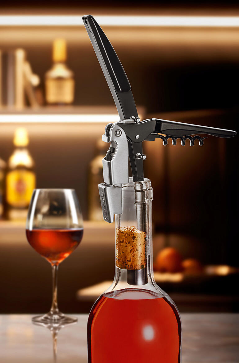 Weinflasche mit Korkenzieher, der auf einem Tisch in einer Restaurantumgebung steht.