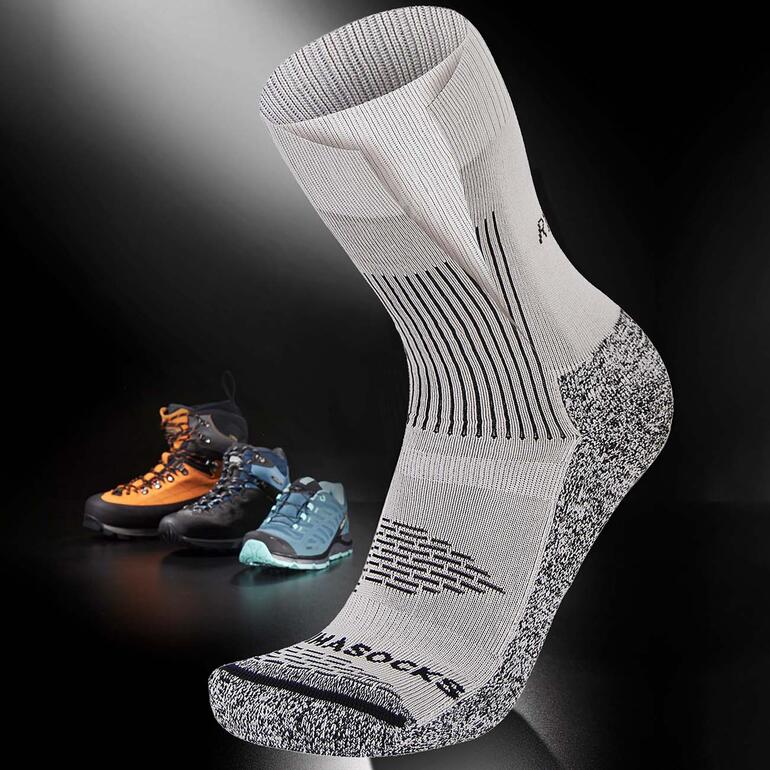 Antiblasen-Socke auf schwarzem Hintergrund mit Bergschuhen im Hintergrund.