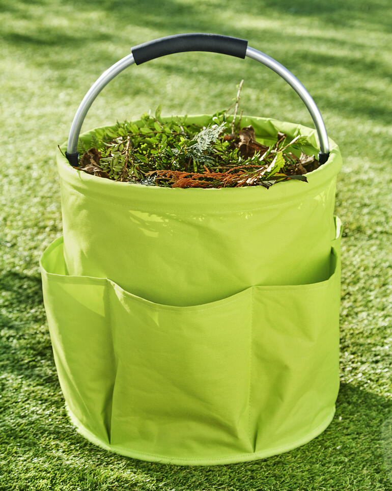 Garten Caddy gefüllt mit Pflanzenabfällen auf grünem Gras.