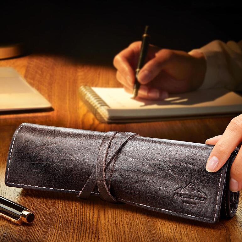 Braunes Stifte-Etui aus Leder mit Schreibutensilien beim Schreiben.