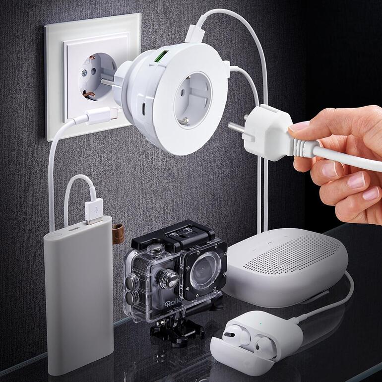 Steckdoseneinsatz mit 4 USB-Ports und angeschlossenen Geräten auf einem Tisch.
