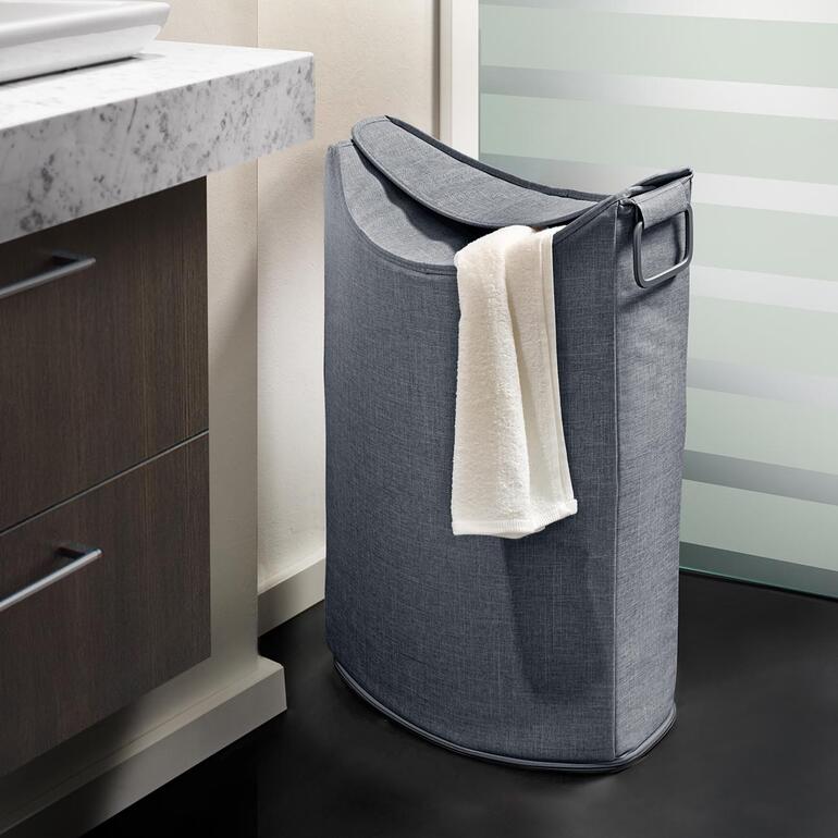 Grauer Wäschesammler neben einem Waschbecken