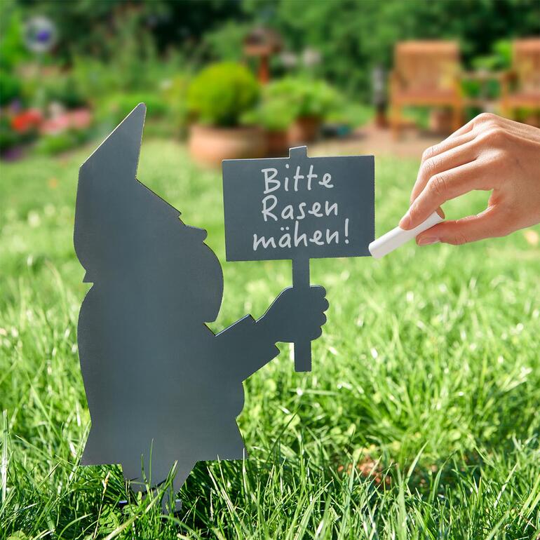 Gartenzwerg mit Schild 'Bitte Rasen mähen' auf einer Wiese