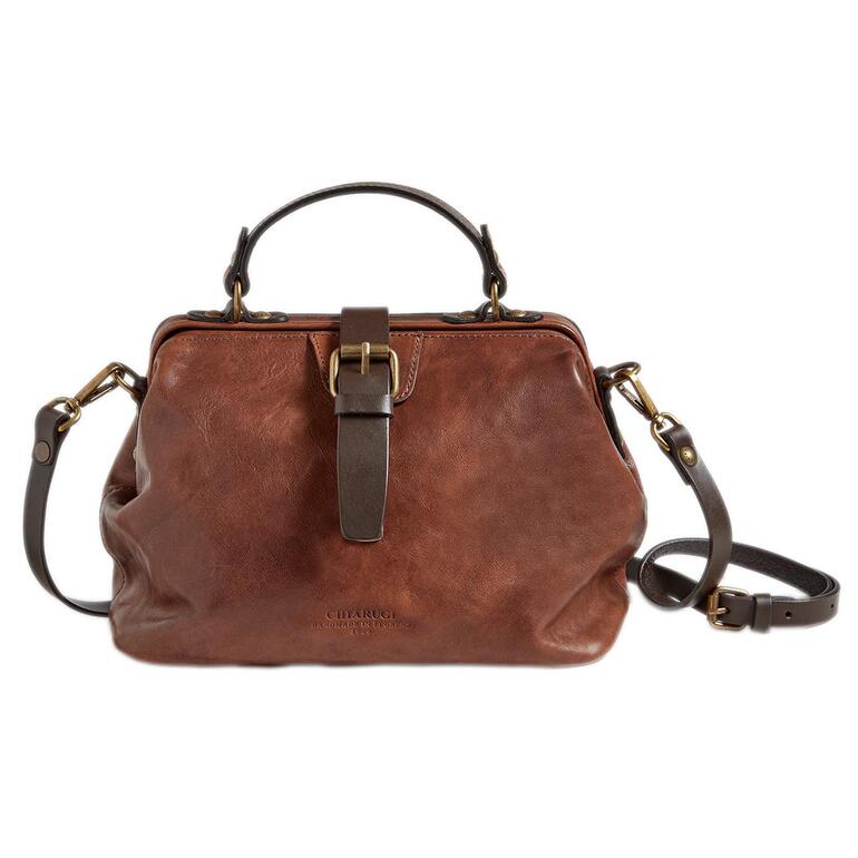 Das Leder wird noch traditionell durch Glanzstoßen mit Bernsteinrollen zugerichtet, so wird es angenehm griffig und die Narbung tritt ausdrucksvoll hervor. Brauner Doctor Bag auf einem weißen Hintergrund