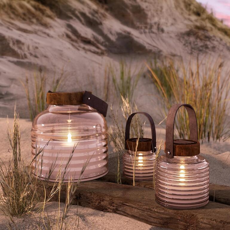 Drei Solarkerzengläser in einem sandigen Landschaftssetting