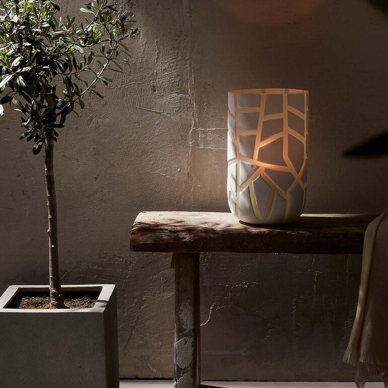 Vase auf einem Tisch, beleuchtet, mit dekorativen Ausschnitten