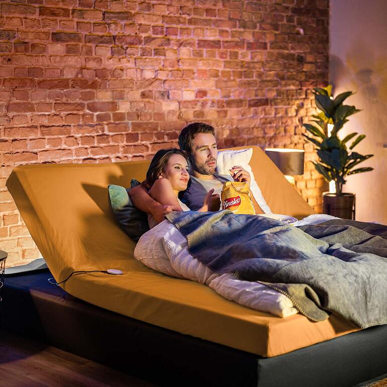 CosyLift Paar schaut zusammen einen Film in einem adaptiven Bett, das elektrischen Komfort bietet