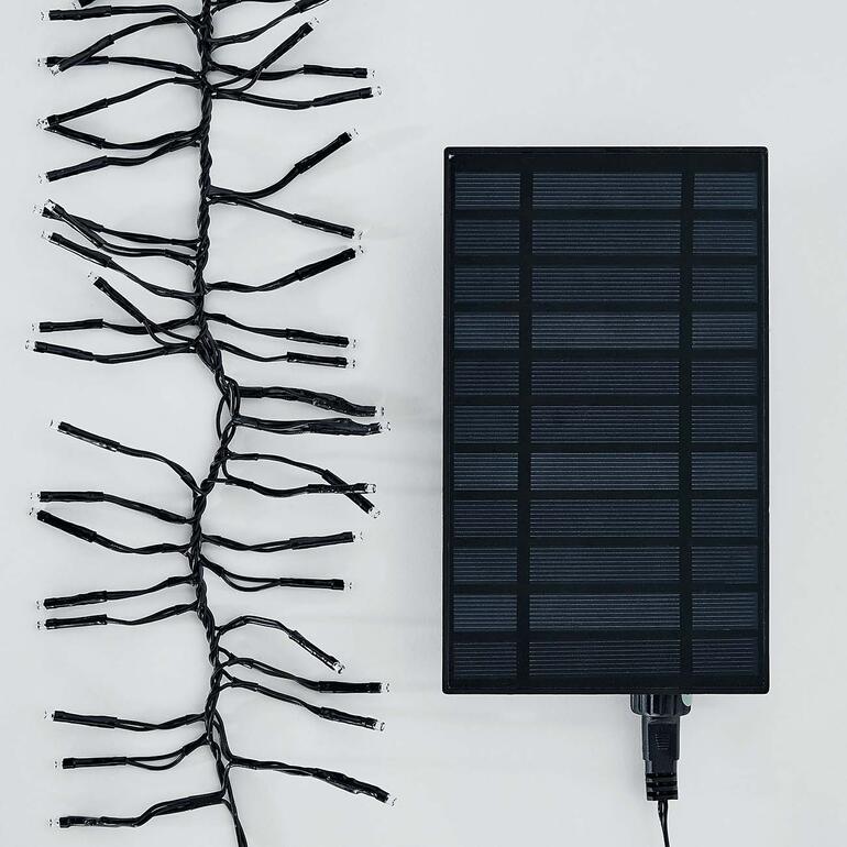 Üppiger Lichterglanz – gespeist von einem hocheffizienten Solarpanel. Solar-Lichterkette und Solarpanel auf einem weißen Hintergrund.