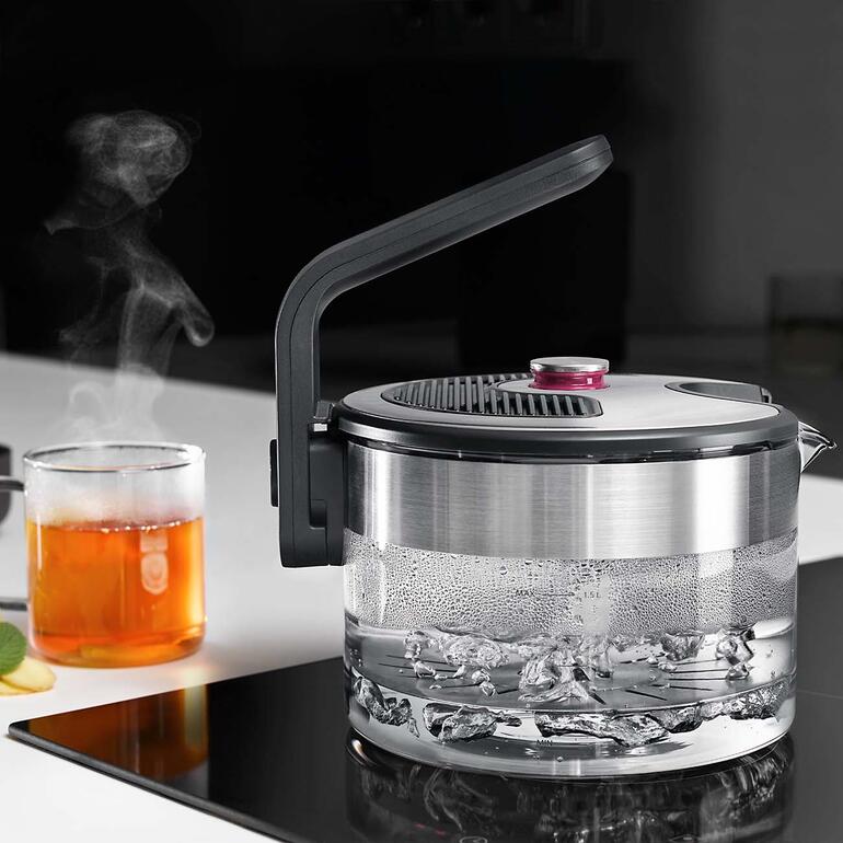 Induktions-Wasserkocher mit dampfendem Wasser auf dem Herd.
