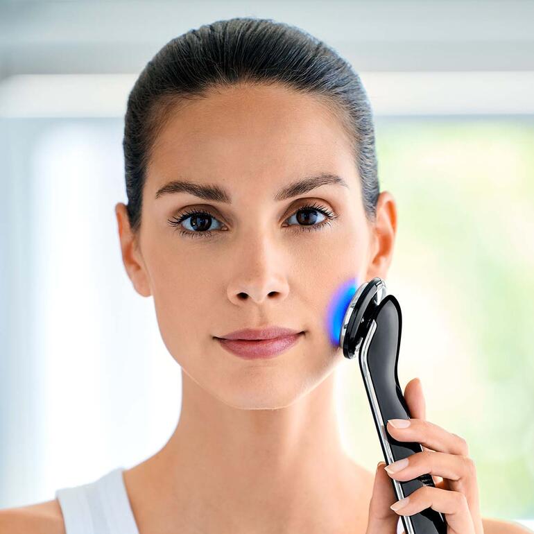 Frau verwendet ein Beauty-Treatment-Set mit einem LED-Gerät