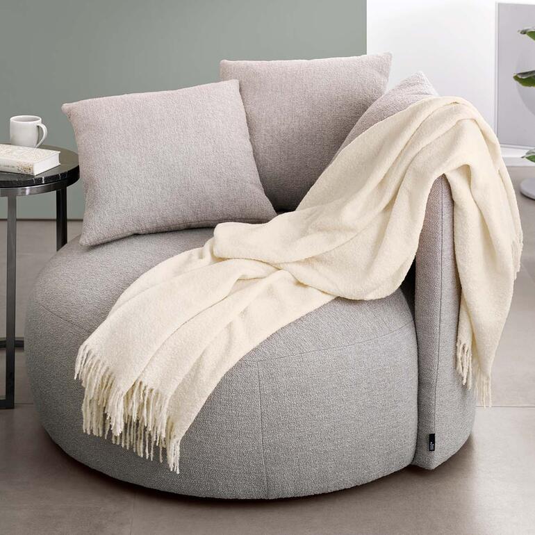 Alpaka-Bouclédecke auf einem gepolsterten Stuhl.