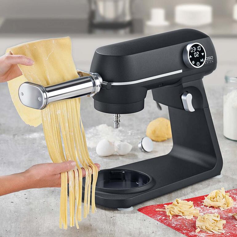 Küchenmaschine mit Fettuccine-Schneider, während frische Nudeln heruntergezogen werden.