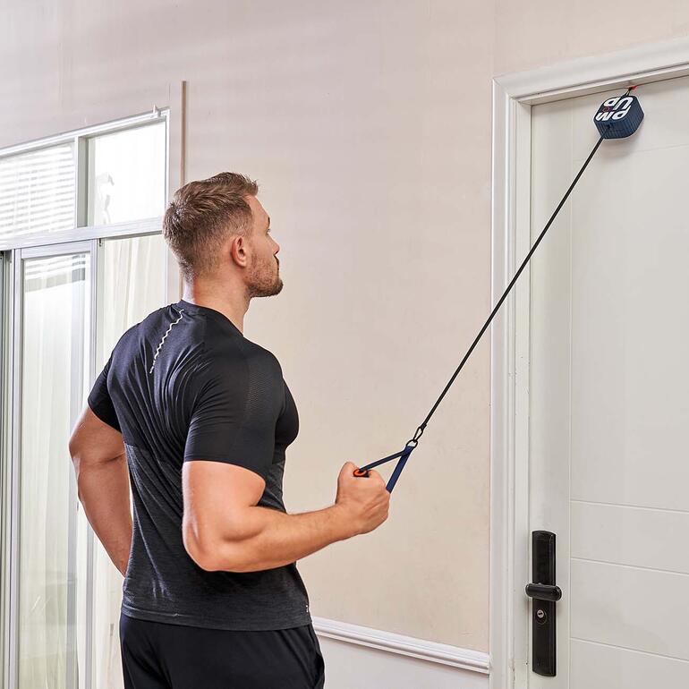 Ihr Pocket-Gym lässt sich einfach in jeder beliebigen Tür verankern. Mann mit kurzer Frisur zieht das Pocket-Gym Gerät in einer Tür.