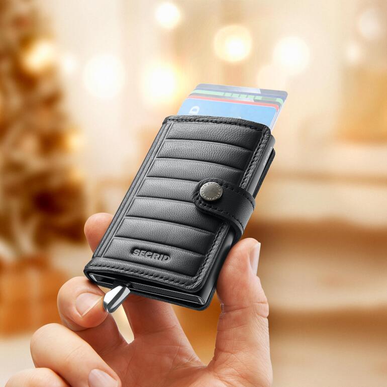 Schwarzes Secrid Mini-Wallet Premium in Hand mit Karten sichtbar.