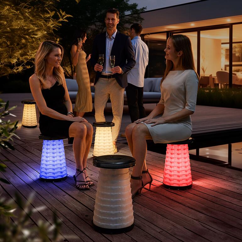 Zwei Frauen sitzen auf LED-Teleskop-Hockern in einer Gartenparty-Atmosphäre.