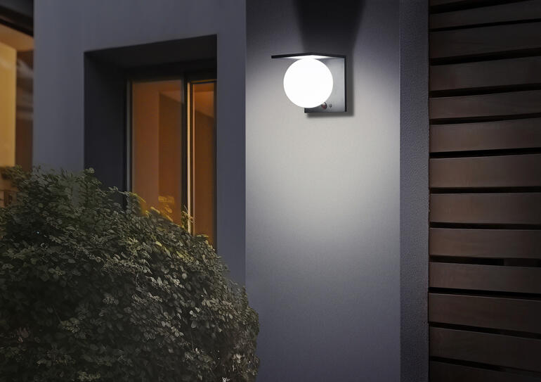 Solar-Kugelwandleuchte an einer Hauswand leuchtet sanft.