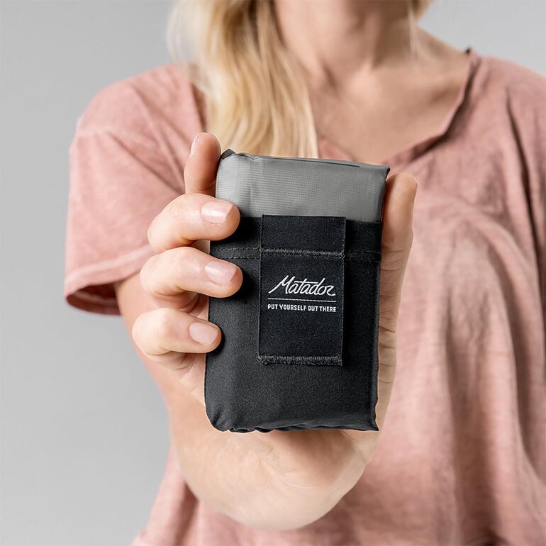 Die Decke ist 108 g leicht und gefaltet gerade mal 12 x 7,6 x 2,8 cm groß. Hand hält zusammengefaltete Ultraleicht-Taschen-Decke