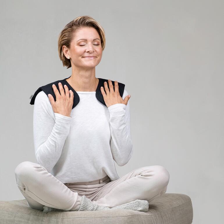 Frau mit Moorkissen auf den Schultern, entspannt