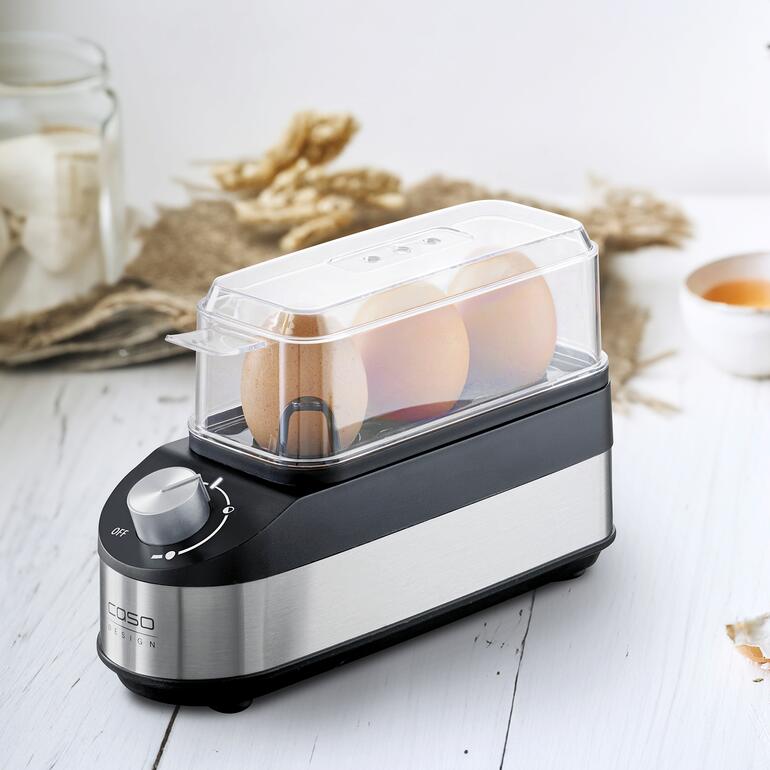 Kompakter Design-Eierkocher mit transparentem Deckel und drei Eiern.