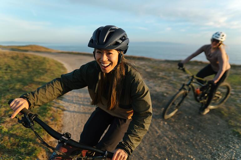 Frau lacht auf dem Fahrrad, trägt einen Helm mit Intercom-System.