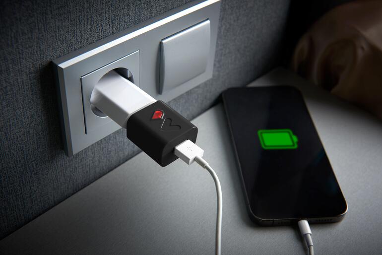 Akku-Schoner in Schwarz, auf einer Ladestation mit aufgeladenem Smartphone.