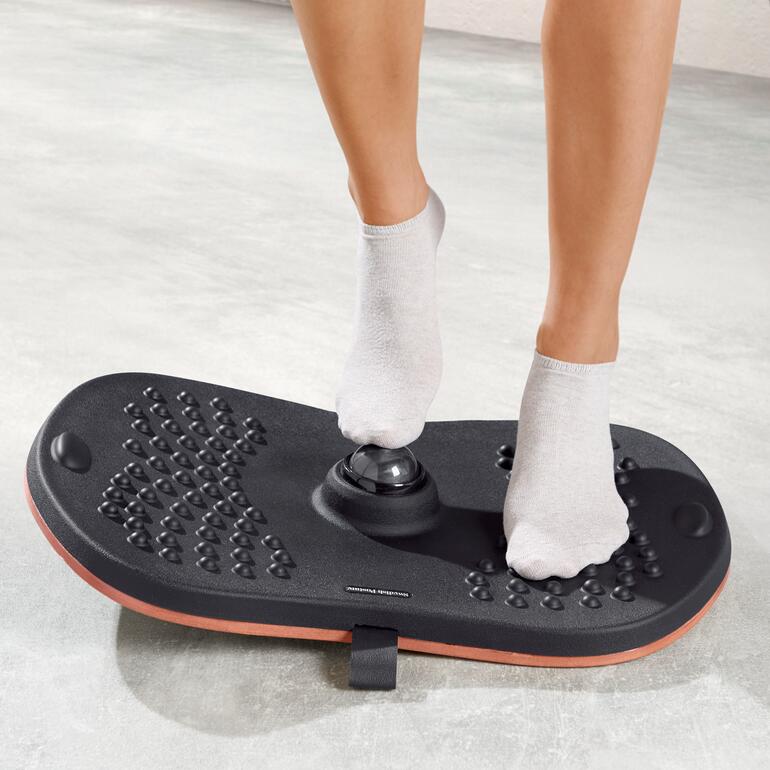 Person steht auf einem Balance-Massage-Board mit Socken.