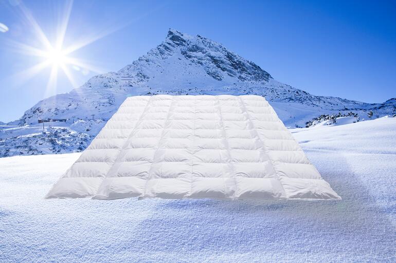 Helle Clima Balancedecke auf schneebedecktem Boden mit Berglandschaft im Hintergrund.