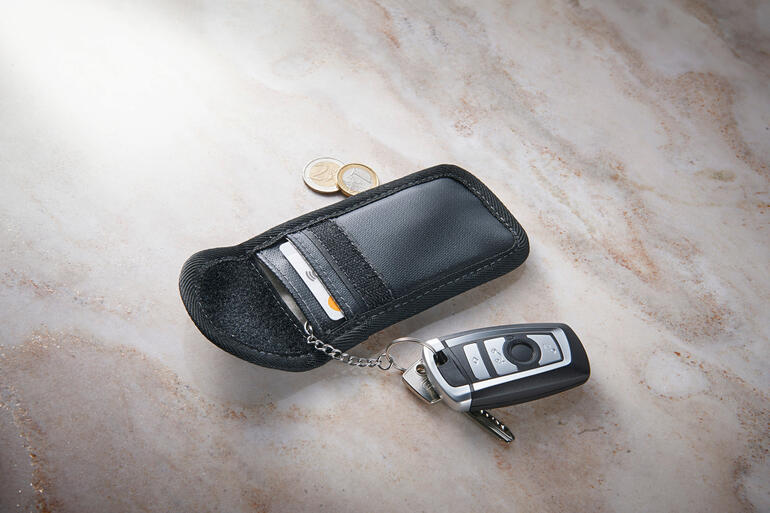 RFID-Schlüssel-Etui mit einem Schlüssel und Euro-Münzen auf einer marmorierten Oberfläche.