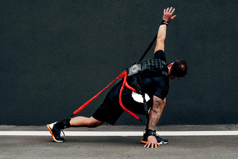 Exopek Pro Widerstands-Trainingsset Mann in sportlicher Pose mit einem Widerstands-Trainingsset an einem urbanen Hintergrund.