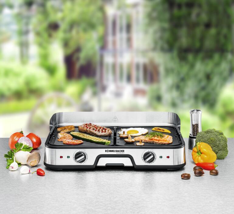 Tischgrill BBQ 2025 auf einem Tisch mit frischen Zutaten und gegrilltem Essen.