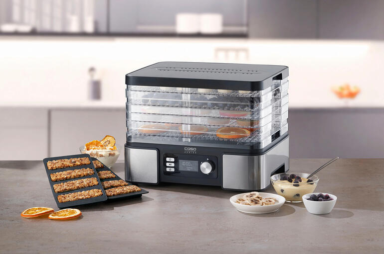 Dörrautomat auf einer Tischplatte mit verschiedenen gesunden Snacks und Zutaten.