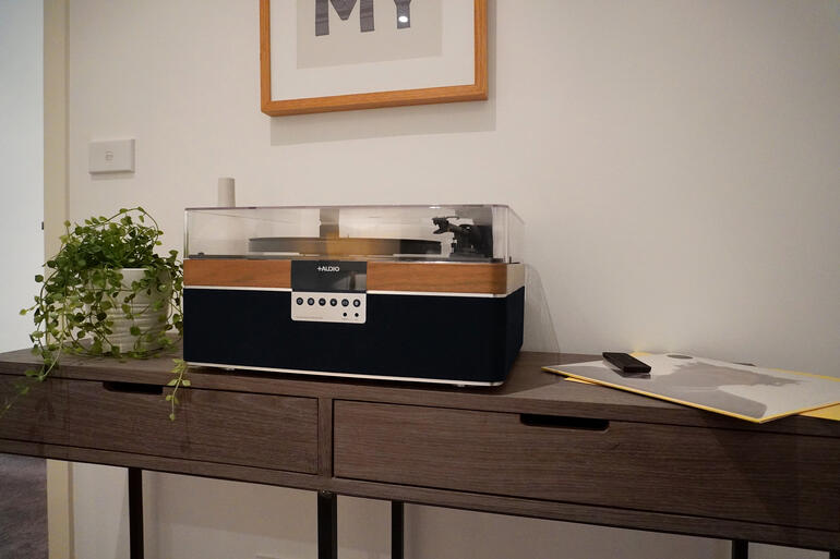 All-In-One-Plattenspieler aus Walnuss auf einem Tisch in einem modernen Raum