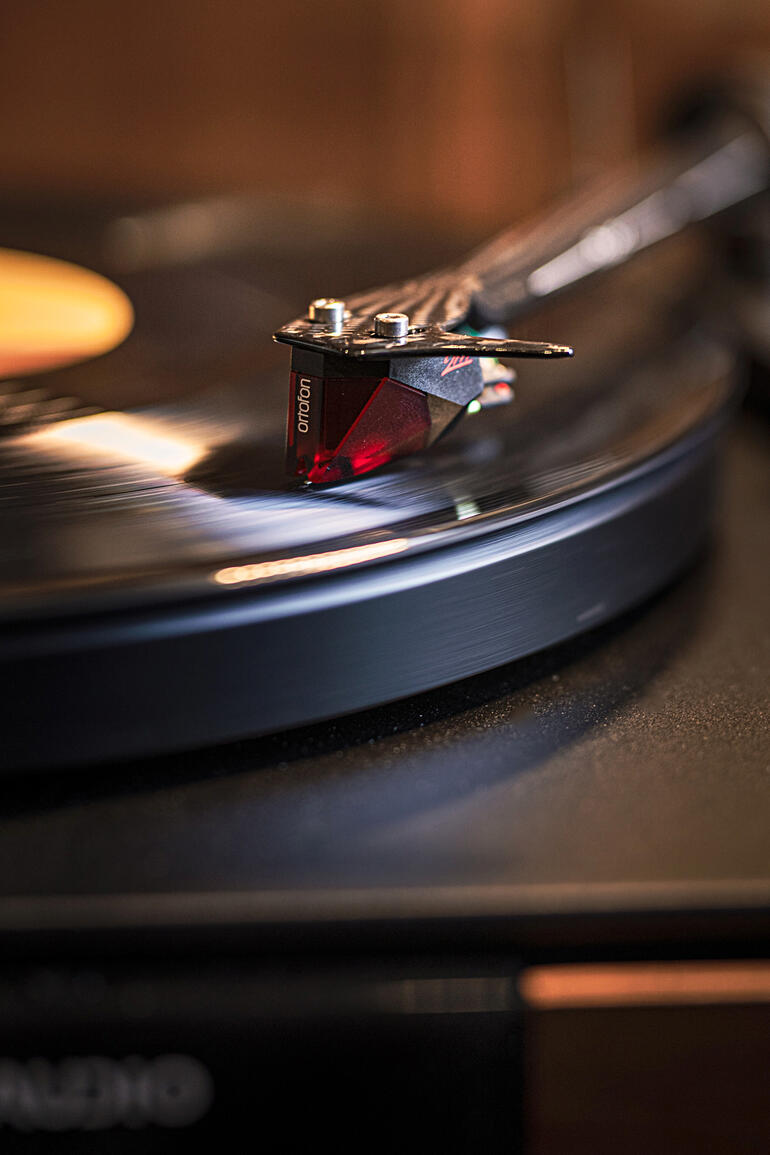Nahaufnahme des Plattenspieler-Tonabnehmers über einer schwarzen Schallplatte