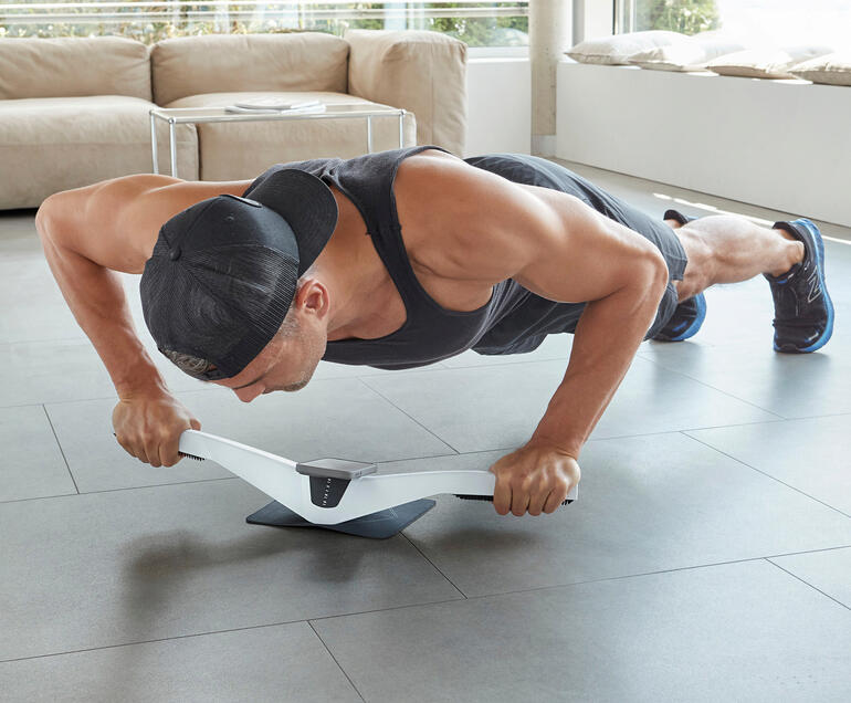 Mann führt Plank-Übung mit Praep® Plank-Trainer auf einem Boden aus.