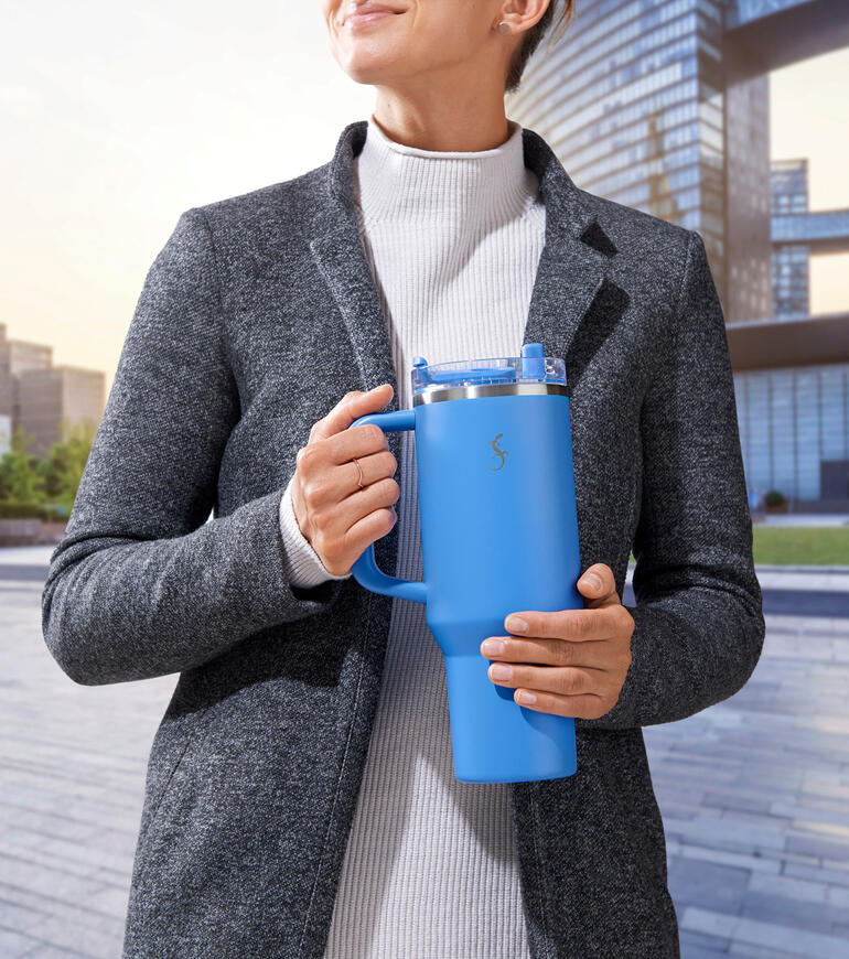 XL-Thermo-Trinkbecher in blau, gehalten von einer Person in grauer Jacke