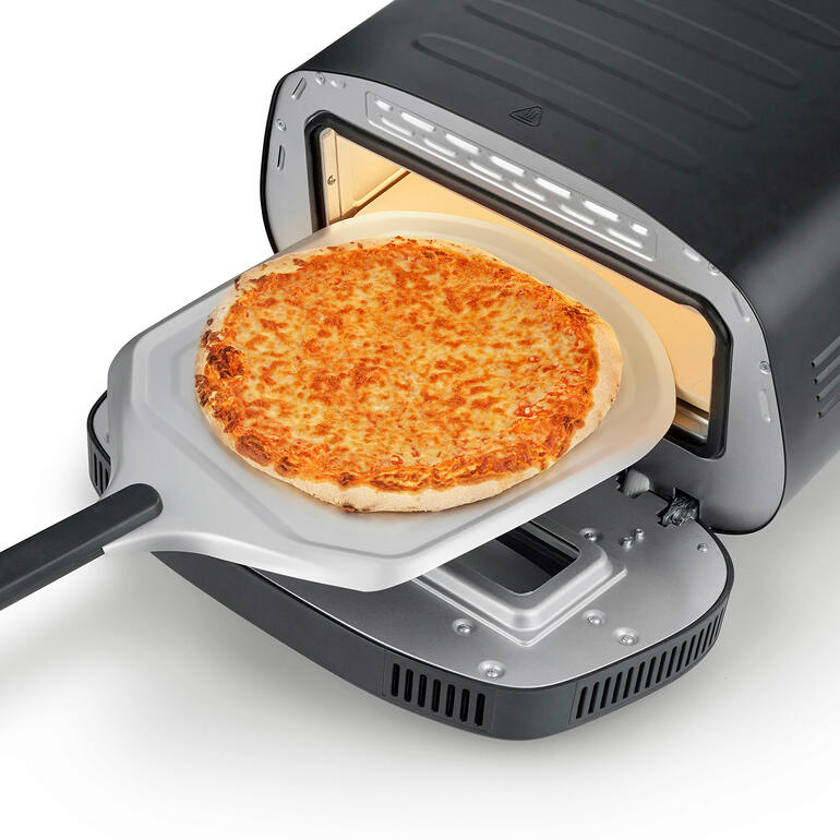 Pizza auf einem Pizzaschieber, wird in den 430 °C Pizzaofen geschoben