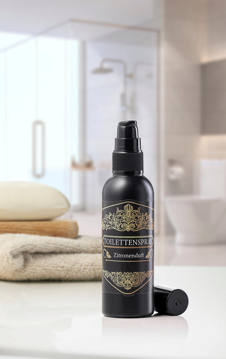 Zitronen-Duft Toilettenspray in schwarzer Flasche auf einem Badetuch.