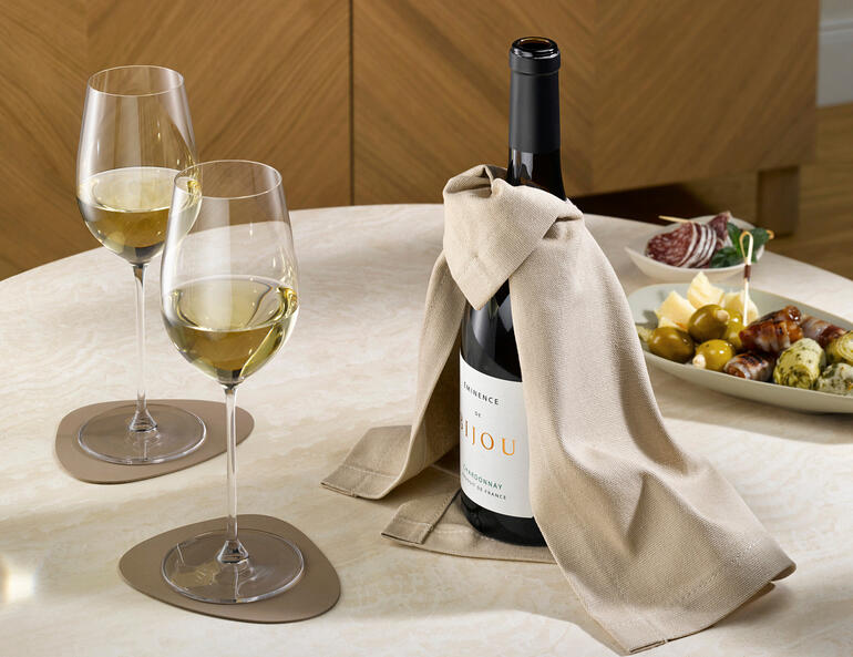 Wein-Cape mit einer Flasche Wein und zwei Gläsern auf einem Tisch.