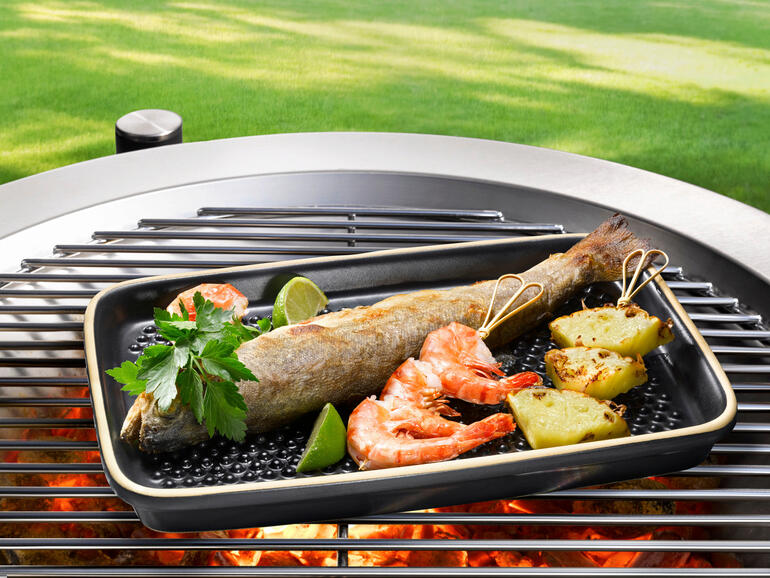 Fisch und Garnelen auf einer Grillplatte im Freien