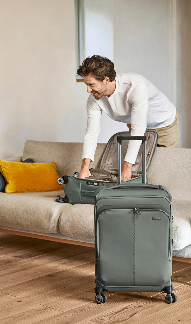 Mann packt einen leichten Travelite Trolley auf ein Sofa.