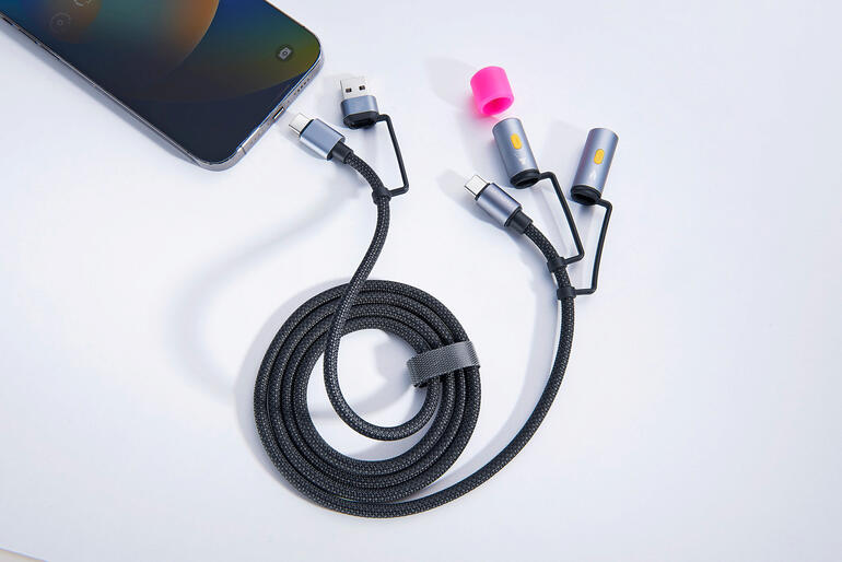 4-in-1 Ladekabel mit mehreren Anschlussmöglichkeiten auf einem Tisch neben einem Smartphone.
