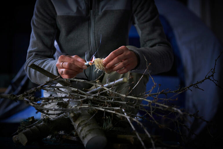Mit dem Anzünder-Adapter entzünden Sie z. B. mit Leichtigkeit ein kleines Lagerfeuer. Person, die in der Natur mit einem Survival-Ladekabel arbeitet.