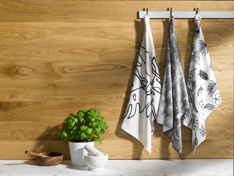 Drei Speed-Dry-Geschirrtücher hängen an einer Holzstange.