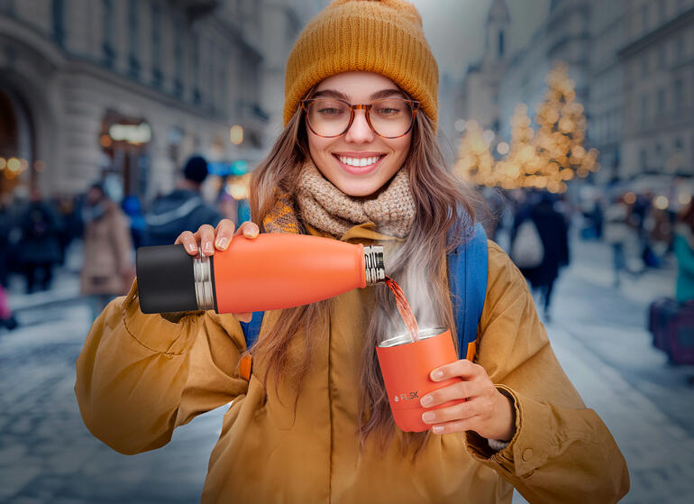 Der Becher ist einfach im Flaschenboden integriert ... Frau auf der Straße gießt aus einer Isolierflasche in einen Becher.