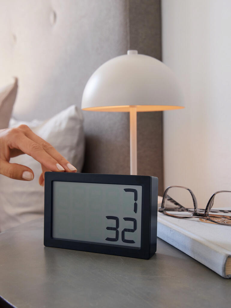 Hand berührt die digitale Tischuhr 