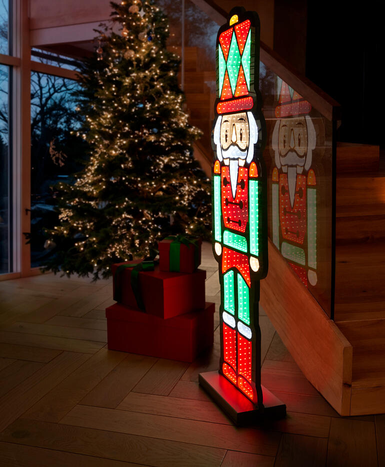 LED-Skulptur eines Nussknackers vor einem Weihnachtsbaum.