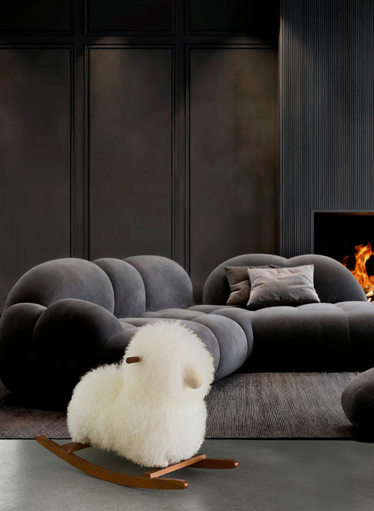 Schaukelschaf aus echtem Fell vor einem modernen Sofa.