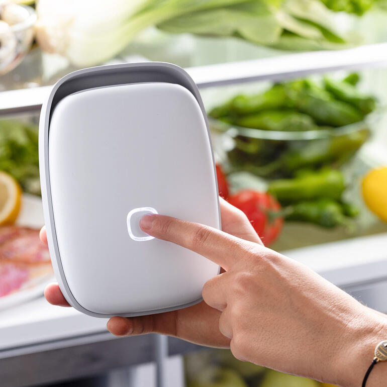 Hand, die den Vitesy Shelfy Kühlschrankreiniger berührt, während er in einen Kühlschrank gezeigt wird.