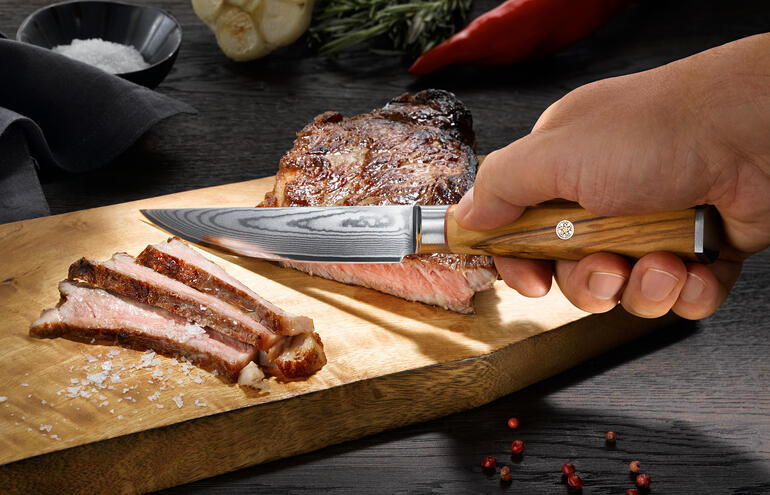 Damast-Steakmesser in Verwendung, perfekt zum Schneiden eines Steaks.